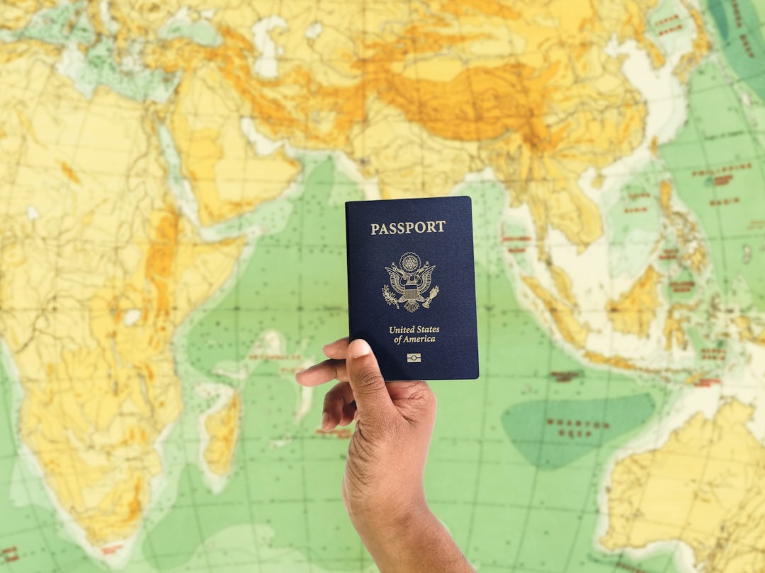 Person holds both a smartphone and a passport, looking thoughtfully at the phone screen, representing the decision to shar...